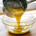 Melted butter being poured into a mixing bowl for cookie dough